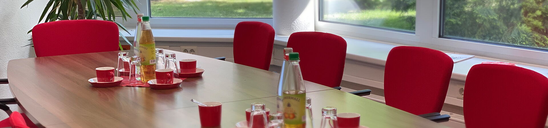 Besprechungstisch mit Getränken und roten Stühlen darum